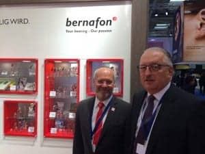 Bruno Keller and Erich Spahr stand in front of a hearing aid history exhibit that celebrates the company's 70th anniversary.