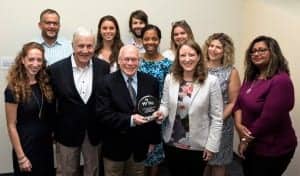Dr. Richard Seewald is handing over the Award to World Wide Hearing Executive Director Audra Renyi and her team.