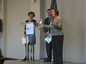 Carole Rogin (at podium) was honored for her nearly four decades of service to HIA and the hearing healthcare field, as Lucille Beck of the Department of Veterans Affairs and HIA President Brandon Sawalich look on.
